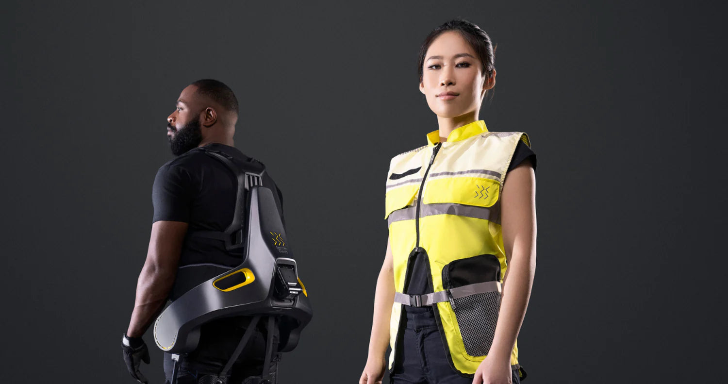 Ein Mann trägt das German Bionic Apogee Exoskelett, das ergonomische Unterstützung für den unteren Rücken bietet, während eine Frau in einer gelben High-Visibility-Weste mit reflektierenden Streifen selbstbewusst in die Kamera blickt. – Jetzt erhältlich im MTN Shop DE.