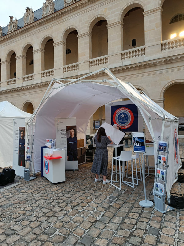 Складна конструкція для заходів Konligo AK470 із внутрішньою білою мембраною, яка використовується як інформаційний стенд на відкритому повітрі в історичному місці, з рекламними дисплеями та сидіннями, тепер доступна на MTN SHOP US.