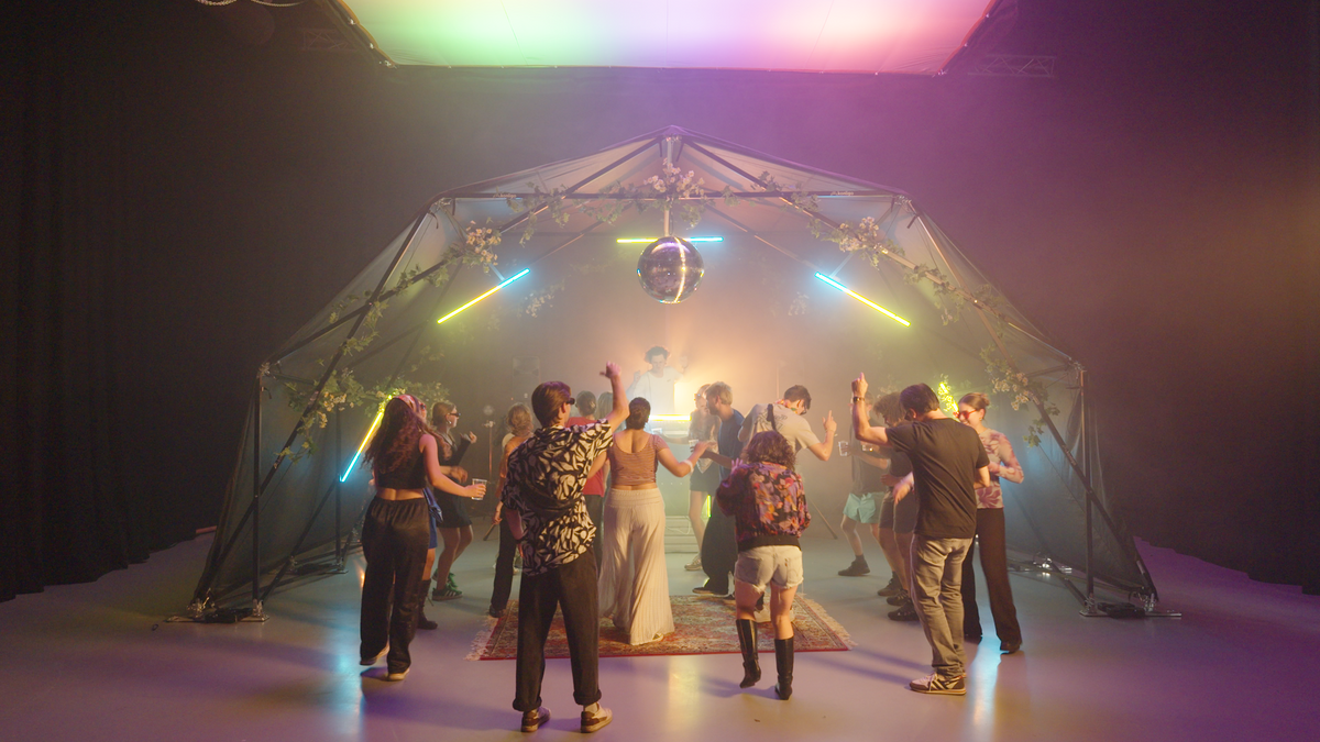 Konligo Fastival event structure with black backdrop and black frame decorated with flowers and neon lights hosting a lively indoor dance party with DJ and disco ball, now available on MTN SHOP US. - imagen 10