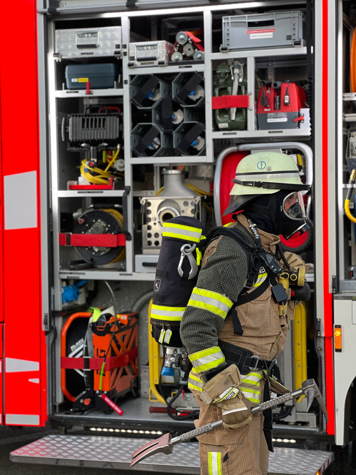Einsatzkraft vor dem geöffneten Geräteraum eines Feuerwehrfahrzeugs, Einsatzumgebung des TEE-UU VARIO Feuerwehrmehrzweckbeutels. - imagen 9